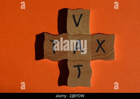 Taxes et TVA, mots en lettres de l'alphabet en bois en forme de mots croisés isolés sur fond orange Banque D'Images