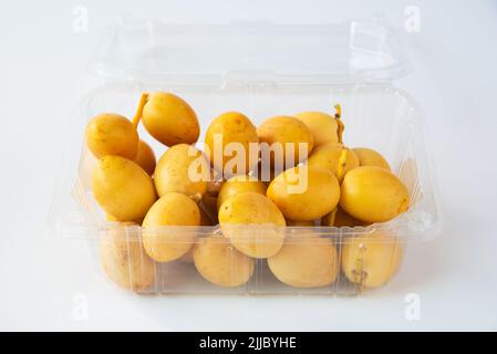 Délicieux fruits frais au palmier dans un emballage en plastique sur fond blanc Banque D'Images