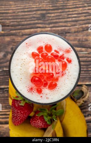 Smoothie à la banane, aux fraises et à l'ananas sur une table en bois et thé moussant ou boules de thé boba Banque D'Images