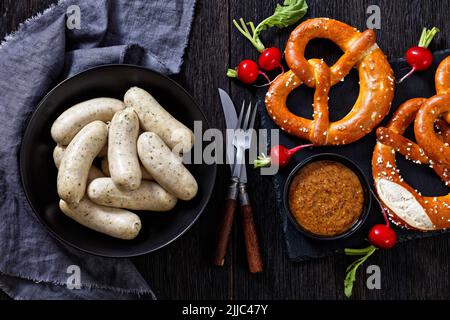 Weisswurst traditionnel dans un bol noir, saucisses blanches de veau haché, bacon de porc, épices et persil, servi avec de la moutarde douce, des bretzels doux, fr Banque D'Images