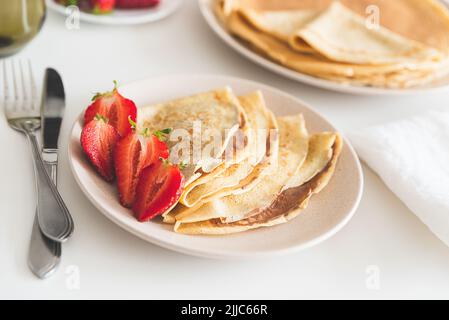 Crêpes françaises avec tartinade au chocolat et fraises sur table blanche Banque D'Images