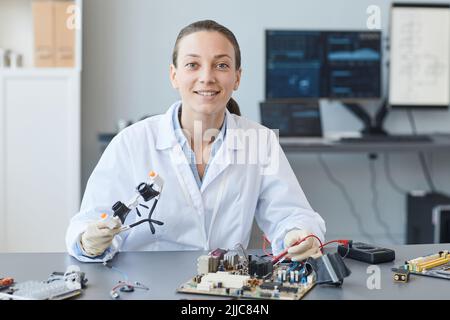 Portrait d'une jeune femme souriante en tant qu'ingénieure regardant l'appareil photo tout en travaillant dans un laboratoire, espace de copie Banque D'Images