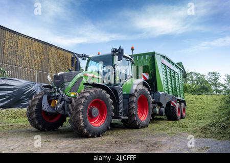 Un tracteur et une remorque qui renversent l'herbe récoltée dans une fosse d'ensilage d'une exploitation laitière, Dumfries, Écosse, Royaume-Uni. Banque D'Images