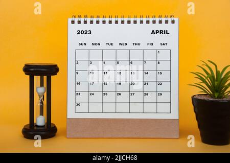 Calendrier du bureau du 2023 avril avec plante de table et verre minutes sur fond jaune. Concept de calendrier Banque D'Images