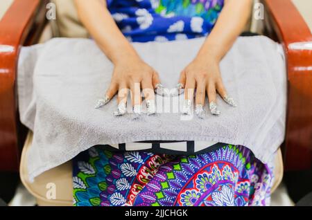 Une femme se fait manucure dans un salon de beauté avec ses ongles recouverts de papier d'aluminium. Banque D'Images