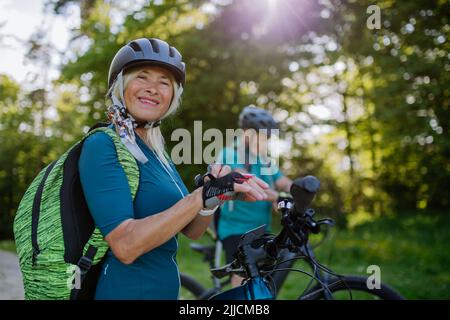 Bonne femme cycliste senior mettant des gants de vélo. Banque D'Images