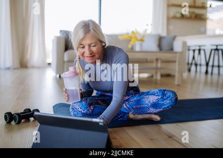 FIT femme senior ayant cours d'exercice en ligne à la maison, concept de style de vie actif. Banque D'Images