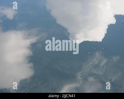 Nuages blancs dans un ciel bleu réfléchis à la surface d'un peu d'eau Banque D'Images