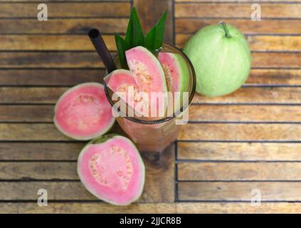Thé de glace de goyave rose sur fond de table en bois avec des tranches de goyave Banque D'Images