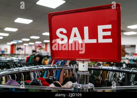 Affiche de solde rouge sur le rail des vêtements dans un magasin ou une boutique de grande rue Banque D'Images