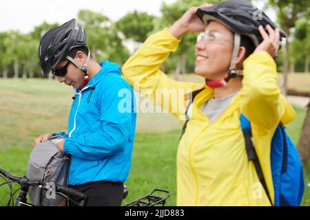 Cycliste dans des lunettes de soleil et un casque de protection en sortant une bouteille d'eau du sac à dos Banque D'Images