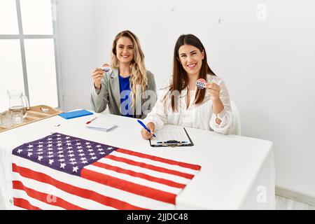 Deux jeunes américaines, portant mon nom, ont voté un badge travaillant à l'université de la table électorale. Banque D'Images