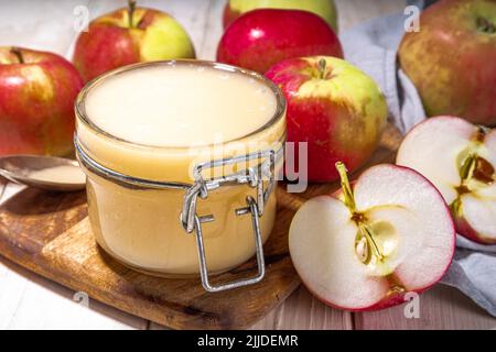 Compote de pommes biologique maison, sauce aux pommes saine dans un petit pot avec pommes fraîches d'été sur fond blanc en bois Banque D'Images