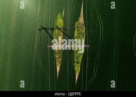 Tour de transport d'électricité et ligne électrique dans le champ agricole, vue de dessus de drone pov le jour ensoleillé du printemps Banque D'Images