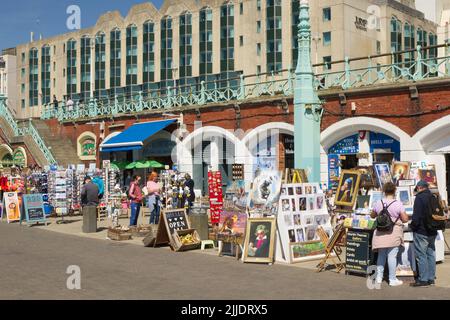 Boutiques touristiques sur la promenade de Brighton Beach, East Sussex, Angleterre. Avec les affichages de navigation de personnes. Banque D'Images