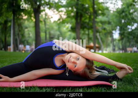 une petite fille exécute des éléments de yoga penchée sur le côté étirant son bras et s'étirant pour les éléments d'étirement Banque D'Images