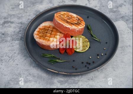 Rouleau de saumon grillé avec mozzarella. Décoration avec vert citron vert et fleurs comestibles Banque D'Images