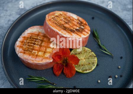 Rouleau de saumon grillé avec mozzarella. Décoration avec vert citron vert et fleurs comestibles Banque D'Images