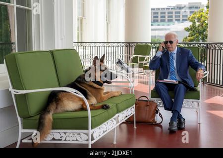 Washington, États-Unis d'Amérique. 25th juillet 2022. Washington, États-Unis d'Amérique. 25 juillet 2022. Le président américain Joe Biden, qui parle sur son téléphone mobile alors que son champ allemand Shepard, se détend sur le canapé, sur le balcon privé de la résidence à la Maison Blanche, 25 juillet 2022, à Washington, DC Biden continue de mettre en quarantaine après avoir obtenu la cote COVID-19. Crédit : Adam Schultz/White House photo/Alay Live News Banque D'Images