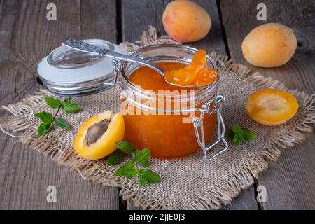 Confiture d'abricots dans un pot en verre sur une ancienne table en bois Banque D'Images