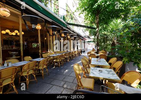 Rue confortable avec tables rondes et chaises lumineuses de café français traditionnel en plein air à Paris Banque D'Images