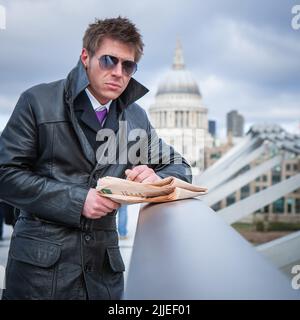 Agent de couverture ; opérations secrètes. Un espion dans une opération secrète sur Millennium Bridge, Londres; d'une série d'images avec le même caractère. Banque D'Images