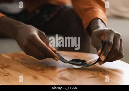 Concept de technologie moderne. Les mains noires des hommes mettent la montre intelligente en charge sans fil avec écran noir Banque D'Images