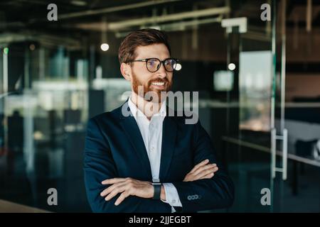 Portrait d'un homme d'affaires réussi en costume posant avec des mains croisées, regardant loin et souriant, espace de copie Banque D'Images