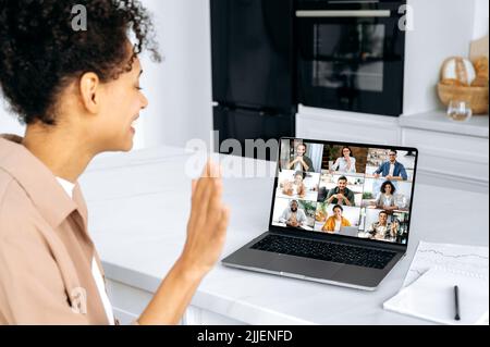 Réunion virtuelle, remue-méninges de collègues, conversation en ligne. Une jeune femme afro-américaine salue ses interlocuteurs, s'entretient par vidéoconférence avec un groupe d'affaires multiracial, discutant du projet Banque D'Images