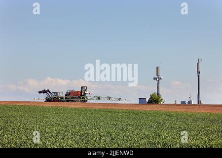 Agriculteur pulvérisant le champ avec du glyphosate, des mâts de téléphone mobile en arrière-plan, Allemagne, Bavière, Erdinger Moos Banque D'Images