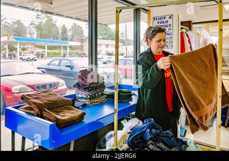 Une femme plie la blanchisserie à une laverie automatique, le 23 février 2013, à Columbus, Mississippi. Le travail paie le salaire minimum. Banque D'Images