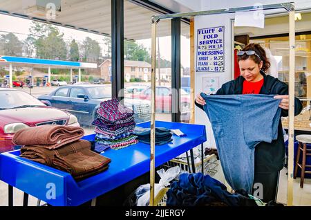 Une femme plie la blanchisserie à une laverie automatique, le 23 février 2013, à Columbus, Mississippi. Le travail paie le salaire minimum. Banque D'Images