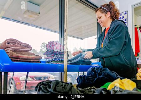 Une femme plie la blanchisserie à une laverie automatique, le 23 février 2013, à Columbus, Mississippi. Le travail paie le salaire minimum. Banque D'Images