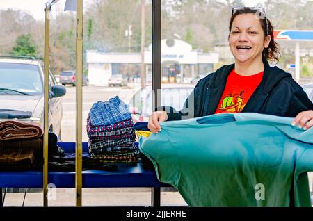 Une femme plie la blanchisserie à une laverie automatique, le 23 février 2013, à Columbus, Mississippi. Le travail paie le salaire minimum. Banque D'Images