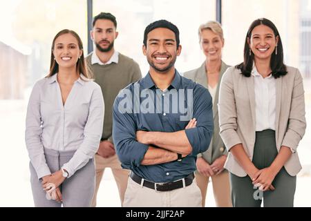 Je dirige ici la meilleure équipe. Un groupe diversifié de gens d'affaires se tenant ensemble au bureau. Banque D'Images