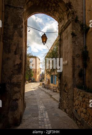 Vieille rue du village de Gruissan, dans le sud de la France, avec une porte ouvrant sur une rue pavée, prise sur un hiver ensoleillé en fin d'après-midi sans pe Banque D'Images