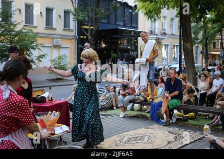 Le public regarde comme acteurs de théâtre exécuter "Odessa, je vous aime" sur le marché du livre à Odessa. La performance "Odessa, je t'aime" raconte des histoires de la vie des habitants d'Odessa avec sa couleur caractéristique et son humour. La représentation a été mise en scène par les acteurs du Théâtre n° 7 et jouée à l'extérieur sur le marché du livre. Le but de cette performance est de recueillir des dons pour les besoins de défense aérienne. Banque D'Images