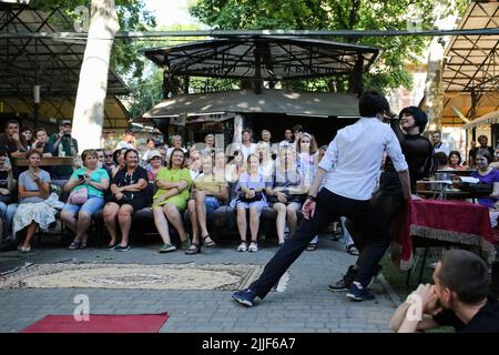 Le public regarde comme acteurs de théâtre exécuter "Odessa, je vous aime" sur le marché du livre à Odessa. La performance "Odessa, je t'aime" raconte des histoires de la vie des habitants d'Odessa avec sa couleur caractéristique et son humour. La représentation a été mise en scène par les acteurs du Théâtre n° 7 et jouée à l'extérieur sur le marché du livre. Le but de cette performance est de recueillir des dons pour les besoins de défense aérienne. Banque D'Images