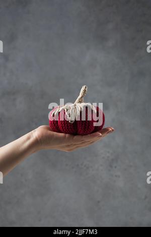 La main d'une femme tient une citrouille tricotée. Automne et agrément. Décoration de bricolage. Banque D'Images