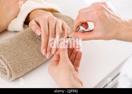 De plus près de la récolte manucuriste anonyme couper cuticules de client sans visage pendant la procédure de beauté dans le salon de lumière moderne Banque D'Images