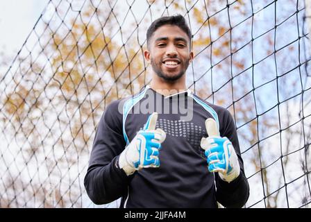 De bonnes choses viennent à ceux qui suent. Un jeune homme jouant au football sur un terrain. Banque D'Images