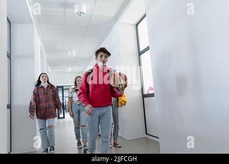 Jeunes élèves du secondaire marchant dans le couloir à l'école, concept de retour à l'école. Banque D'Images