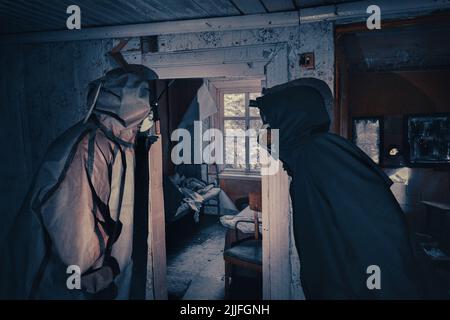 Poster de film fictif. Les gens avec des lampes de poche, des masques et des vêtements de protection inspectent la vieille maison. Personnes infectées épidémiques dans les foyers détruits. Environnement sombre et sombre, traitement du filtre. Banque D'Images