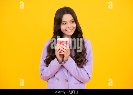 Enfant adolescent avec une tasse de café isolée sur fond jaune studio. Boisson à emporter pour fille. Visage heureux, émotions positives et souriantes de Banque D'Images