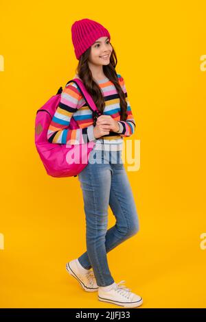 Vacances scolaires d'hiver. Retour à l'école. Adolescente avec chapeau chaud et chandail sur fond jaune isolé studio. École d'hiver. Heureux Banque D'Images