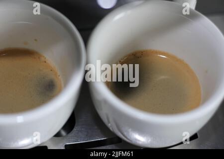 Espresso aromatique fraîchement préparé dans deux tasses blanches. Machine à café cafetière. Banque D'Images