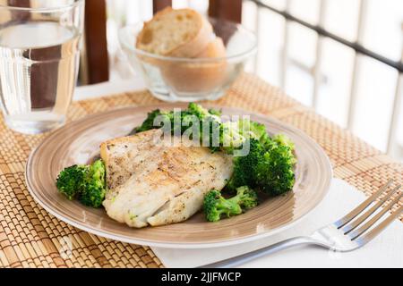 filet de bar frit avec garniture de brocoli sur plaque de pierre chaude noire Banque D'Images