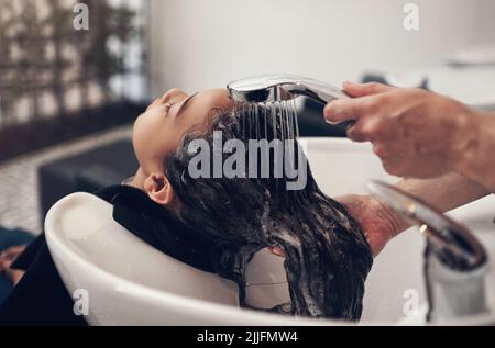 Le rinçage fait toute la différence. Une jeune fille se lavoir ses cheveux au salon. Banque D'Images