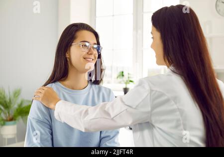 Jeune femme gaie patiente consulte un médecin professionnel assis dans un hôpital moderne Banque D'Images