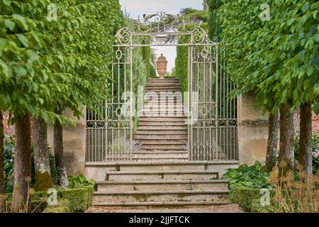 Marches en pierre menant par une porte de jardin très ornée à une urne en pierre Banque D'Images